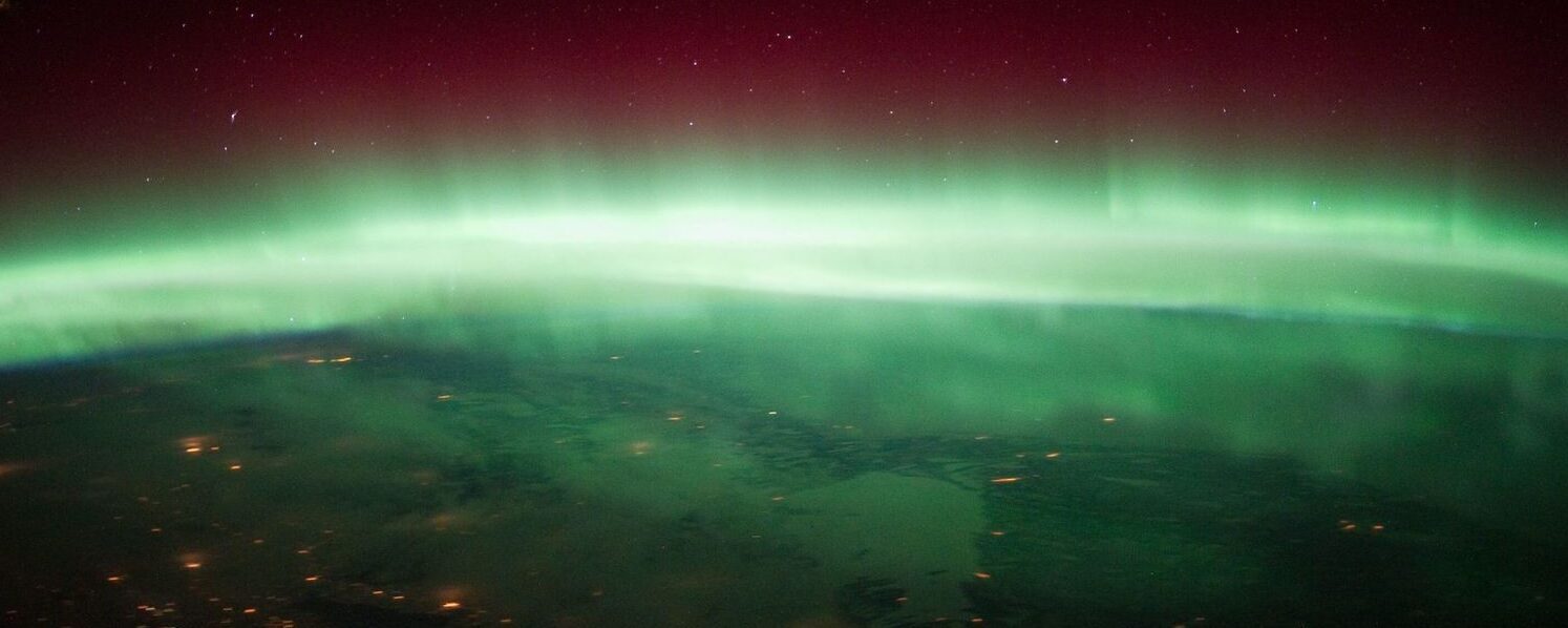 The aurora borealis over a surface of a planet, presumably earth.